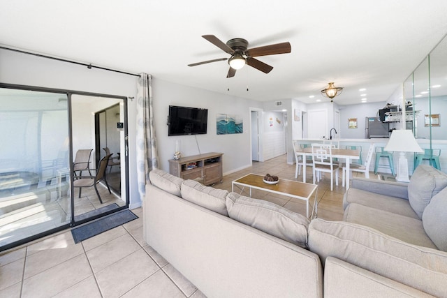 tiled living room with ceiling fan and sink