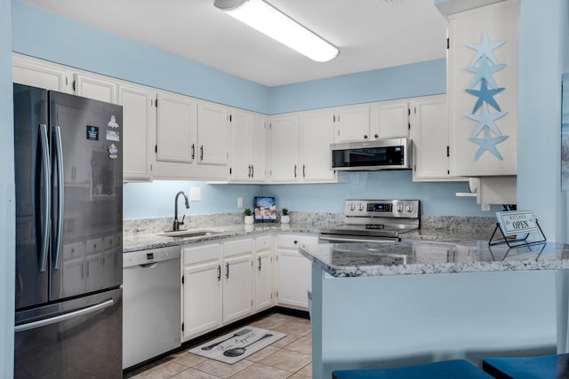 kitchen featuring light stone counters, white cabinetry, appliances with stainless steel finishes, light tile floors, and sink