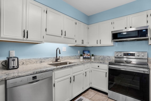 kitchen featuring stainless steel appliances, white cabinetry, sink, and light stone countertops