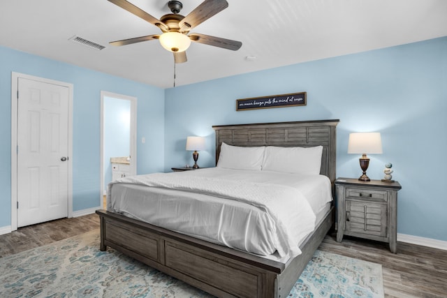 bedroom featuring ceiling fan, dark hardwood / wood-style flooring, and connected bathroom