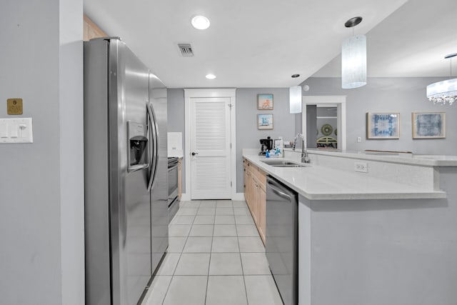 kitchen featuring hanging light fixtures, sink, stainless steel appliances, and light tile floors