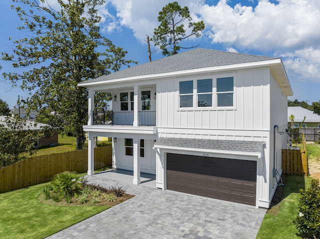 view of front of house featuring a garage, a balcony, and a front lawn