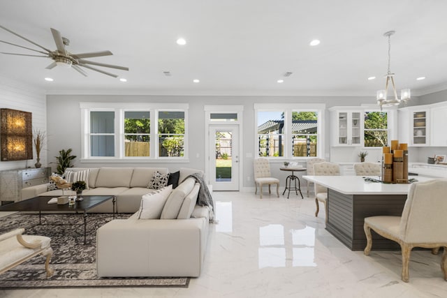 tiled living room with ceiling fan with notable chandelier and crown molding