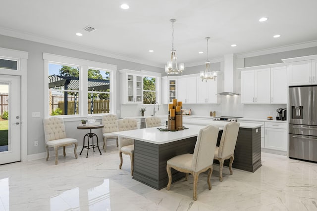 kitchen with a kitchen island, a breakfast bar area, custom range hood, and stainless steel fridge