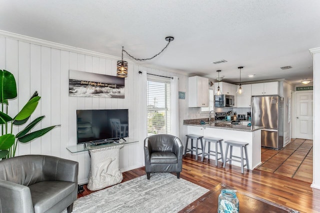 living room featuring sink, dark wood-type flooring, and ornamental molding