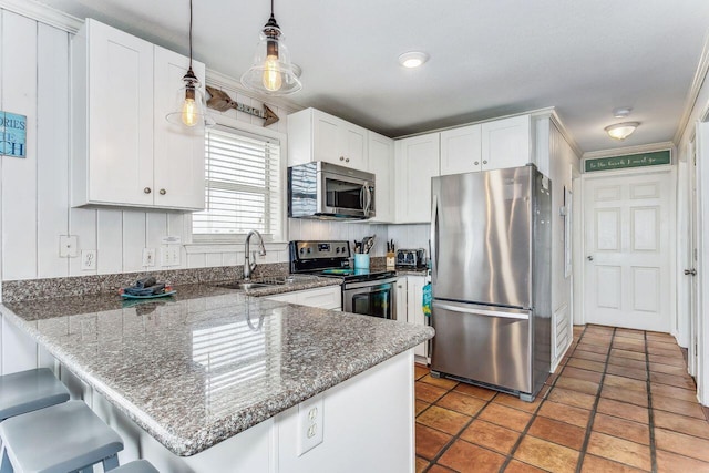 kitchen featuring appliances with stainless steel finishes, white cabinets, hanging light fixtures, crown molding, and a kitchen breakfast bar