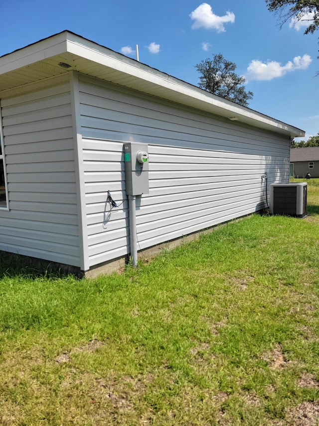 view of property exterior with central AC unit and a yard