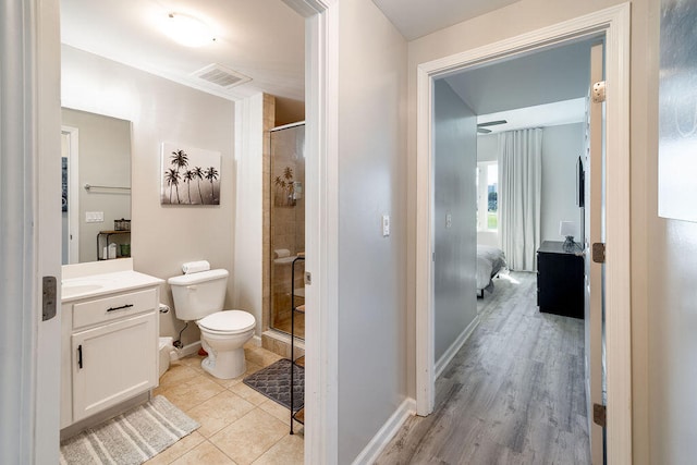 bathroom featuring a shower with shower door, toilet, tile floors, and vanity