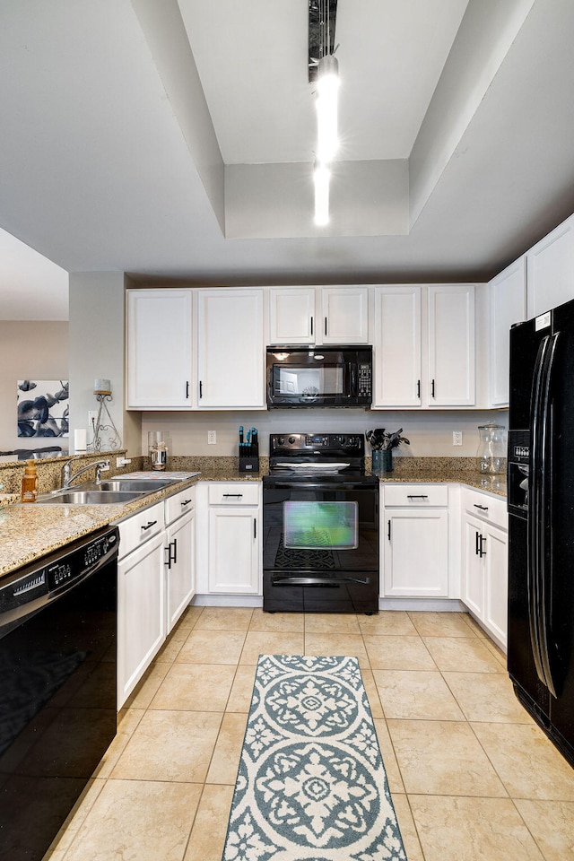 kitchen featuring sink, light tile flooring, black appliances, white cabinetry, and a raised ceiling