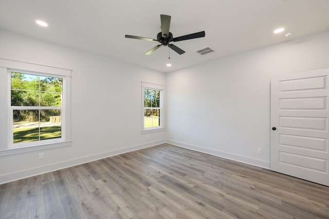 spare room featuring ceiling fan, light wood-type flooring, and a wealth of natural light