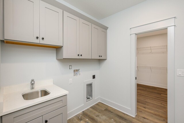 washroom featuring wood-type flooring, electric dryer hookup, hookup for a washing machine, sink, and cabinets