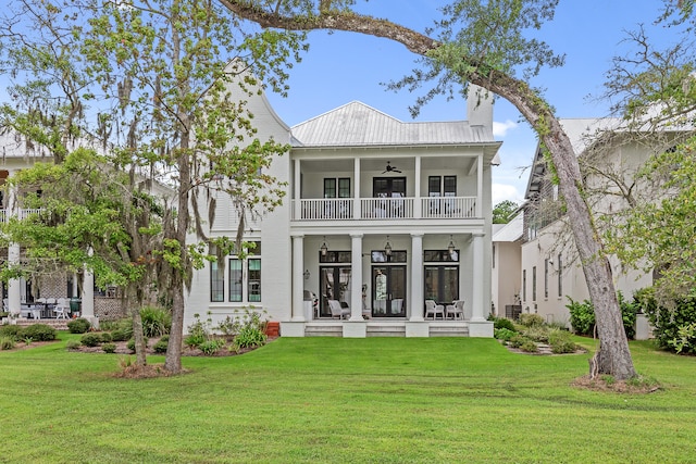 rear view of property with a balcony, a lawn, and ceiling fan