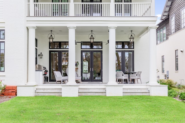 entrance to property with french doors, a balcony, and a lawn