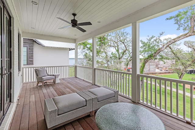 wooden terrace featuring ceiling fan and a lawn