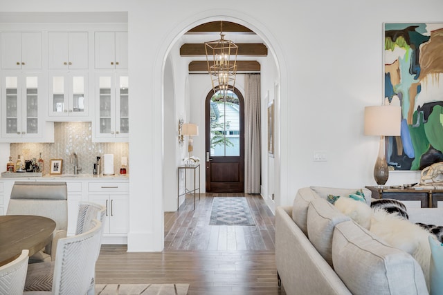 entrance foyer featuring beamed ceiling, light hardwood / wood-style flooring, sink, and an inviting chandelier