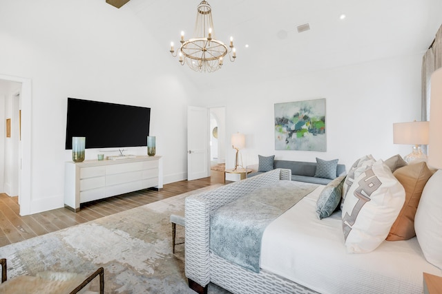 bedroom with light hardwood / wood-style floors, a high ceiling, and an inviting chandelier