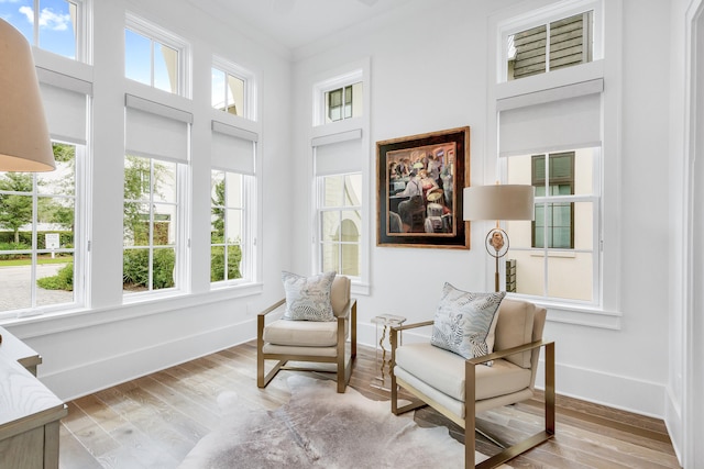 living area with a healthy amount of sunlight, crown molding, and light wood-type flooring