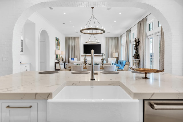 kitchen with a notable chandelier, light stone countertops, and decorative light fixtures