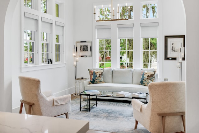 living room with a notable chandelier, a high ceiling, and a healthy amount of sunlight