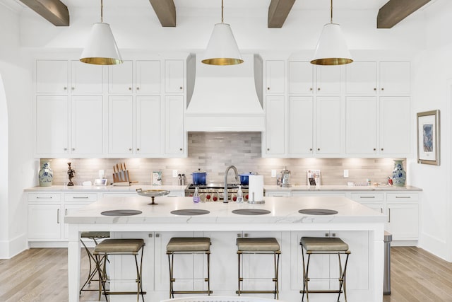 kitchen featuring light hardwood / wood-style floors, beam ceiling, backsplash, and premium range hood