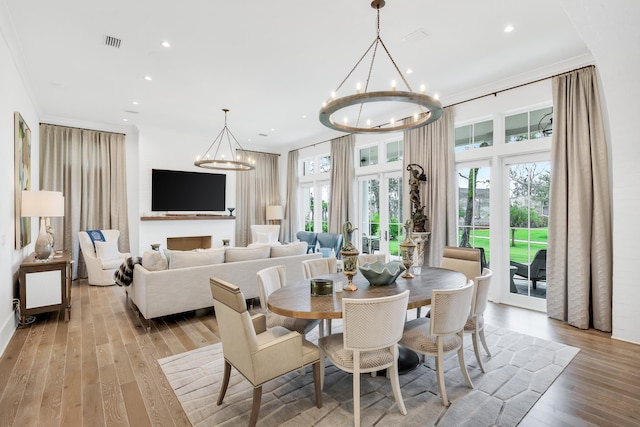 dining room featuring a wealth of natural light, ornamental molding, light hardwood / wood-style flooring, and a notable chandelier