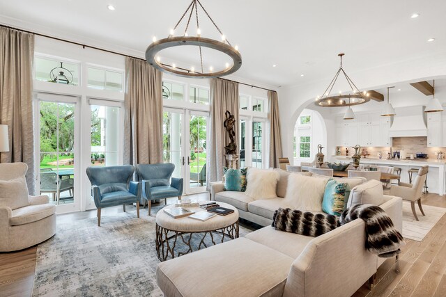 living room featuring light hardwood / wood-style flooring, a chandelier, french doors, and a wealth of natural light