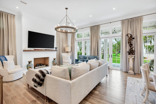 living room featuring an inviting chandelier, crown molding, and light wood-type flooring