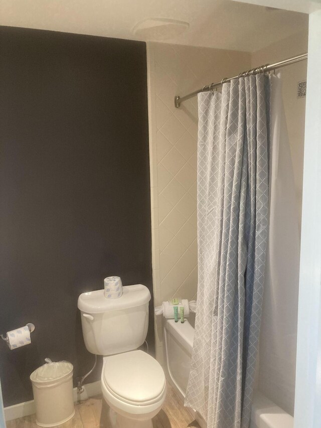 bathroom with shower / tub combo with curtain and toilet