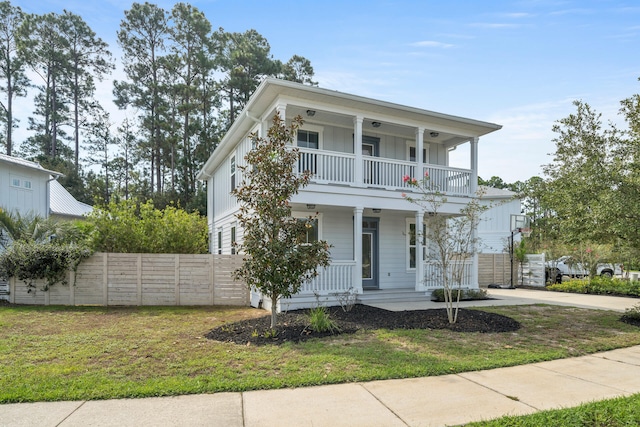 view of front of home featuring a balcony, a porch, and a front yard