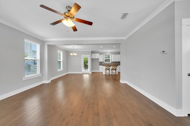 unfurnished living room with ceiling fan with notable chandelier, ornamental molding, and dark hardwood / wood-style flooring