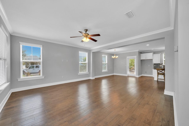 unfurnished living room with a wealth of natural light, crown molding, ceiling fan with notable chandelier, and dark hardwood / wood-style floors