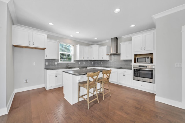 kitchen with a center island, wall chimney exhaust hood, a breakfast bar area, stainless steel appliances, and dark hardwood / wood-style floors