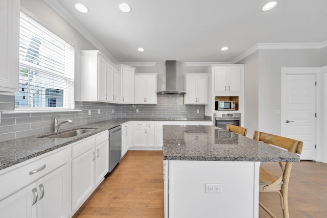 kitchen with a kitchen breakfast bar, light hardwood / wood-style flooring, stainless steel appliances, and wall chimney exhaust hood