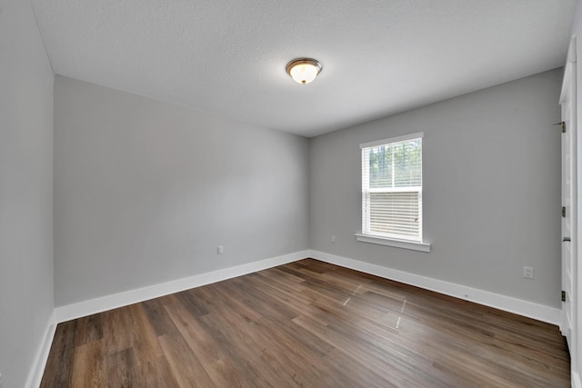 spare room featuring dark hardwood / wood-style flooring and a textured ceiling