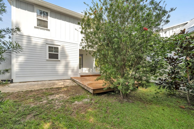 rear view of house featuring a wooden deck and a yard