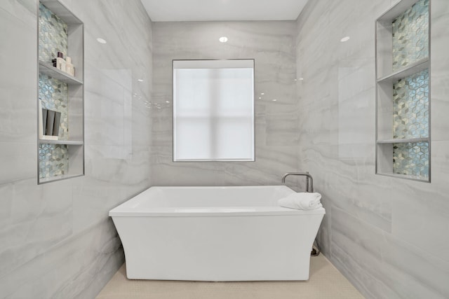 bathroom featuring tile flooring, tile walls, and a bathtub