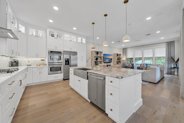 kitchen featuring light hardwood / wood-style flooring, stainless steel appliances, a kitchen island with sink, white cabinetry, and sink