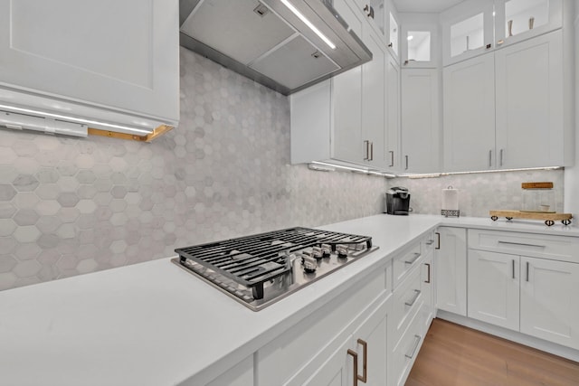 kitchen with premium range hood, light hardwood / wood-style flooring, backsplash, stainless steel gas cooktop, and white cabinetry