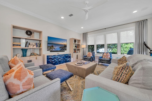 living room featuring wood-type flooring, ceiling fan, built in shelves, and ornamental molding