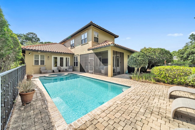 rear view of property featuring a patio area and a pool with hot tub