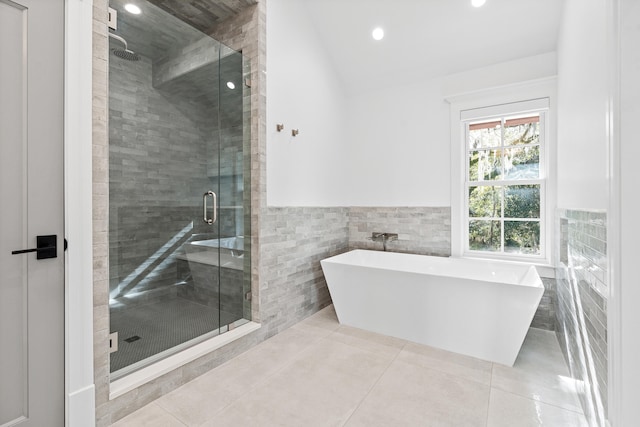 bathroom with tile patterned flooring, plus walk in shower, vaulted ceiling, and tile walls