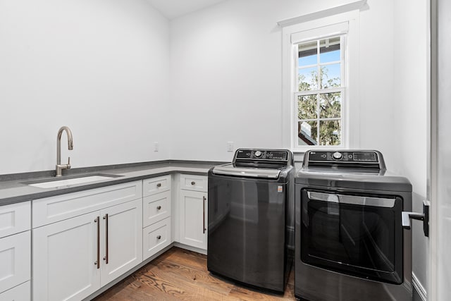 washroom featuring sink, washing machine and dryer, cabinets, and hardwood / wood-style floors