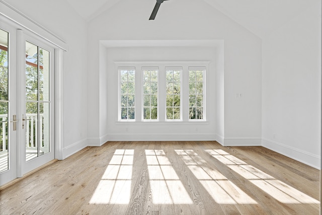 empty room with light wood-type flooring, french doors, and lofted ceiling