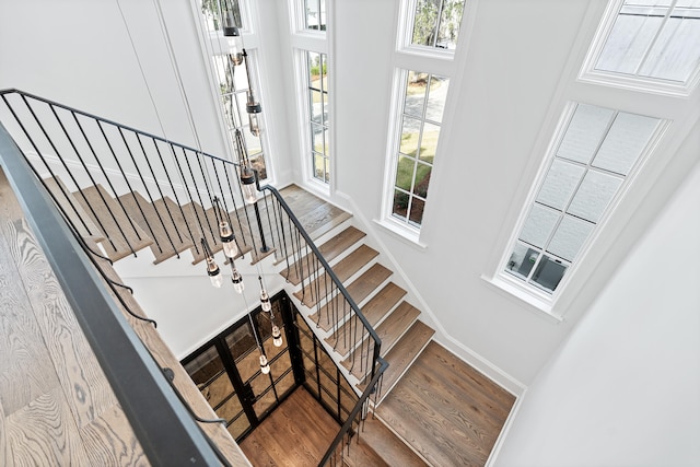 staircase featuring a high ceiling, hardwood / wood-style floors, and cooling unit