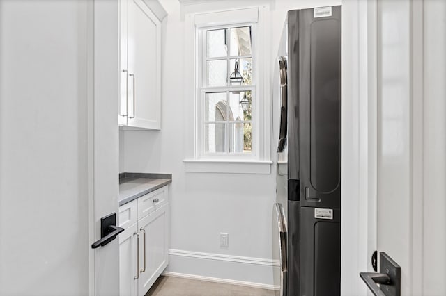 interior space with stacked washer / drying machine and white cabinets