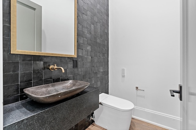 bathroom featuring hardwood / wood-style floors, backsplash, vanity, tile walls, and toilet