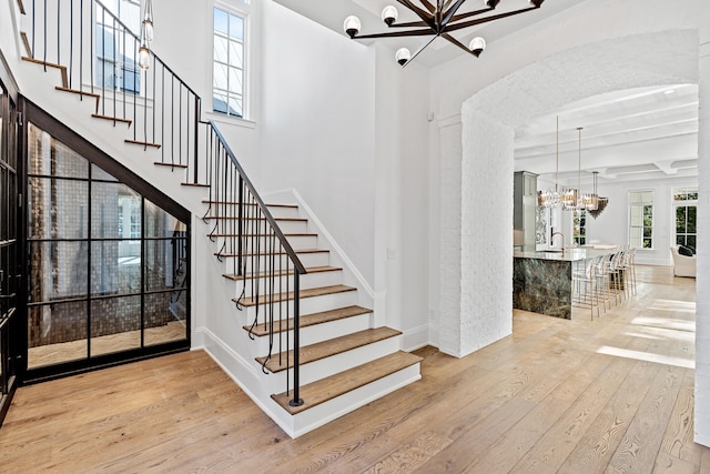 stairway featuring wood-type flooring and an inviting chandelier