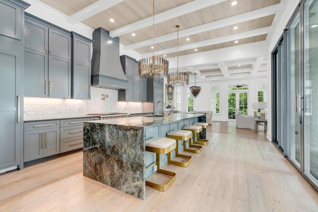 kitchen featuring beamed ceiling, light hardwood / wood-style flooring, dark stone countertops, and custom exhaust hood