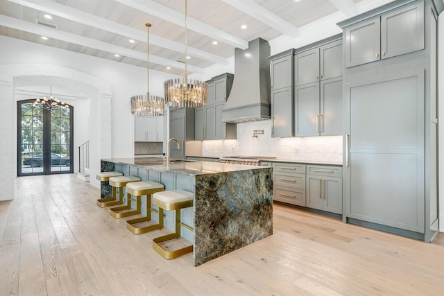 kitchen with dark stone countertops, backsplash, decorative light fixtures, and premium range hood