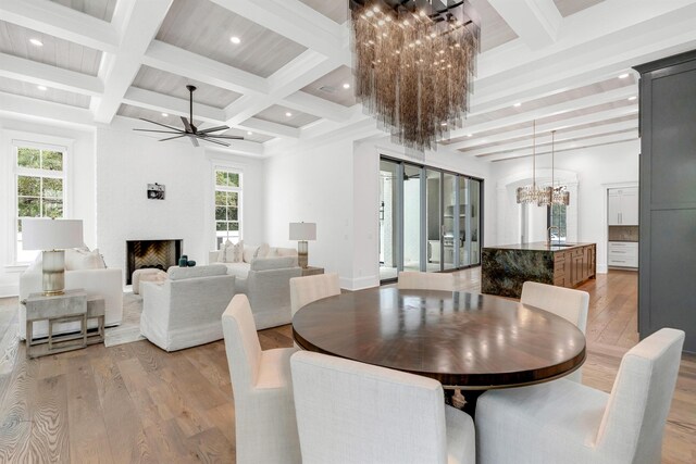 dining area featuring hardwood / wood-style flooring, coffered ceiling, ceiling fan with notable chandelier, and beam ceiling